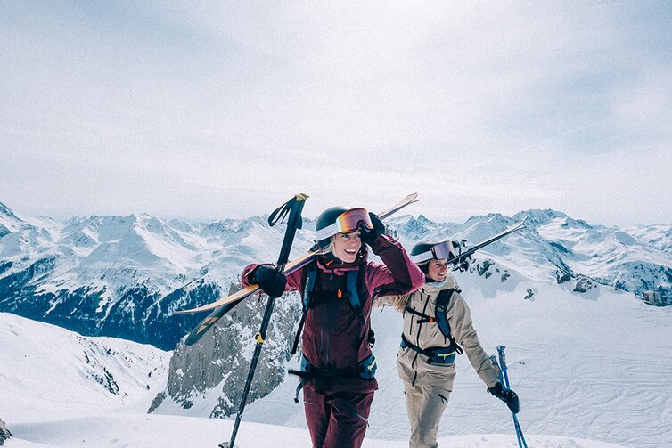 Two people with skiing gear on a snow-covered mountain.