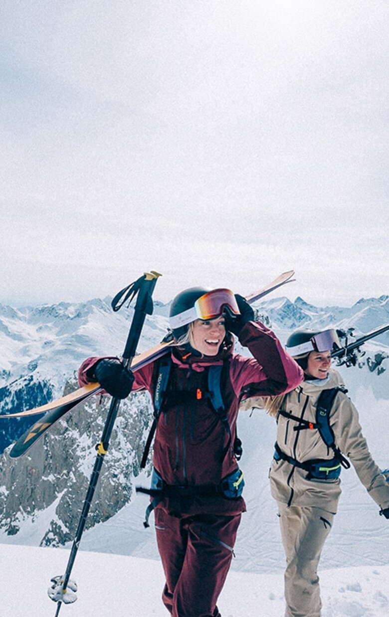 Two people with skiing gear on a snow-covered mountain.