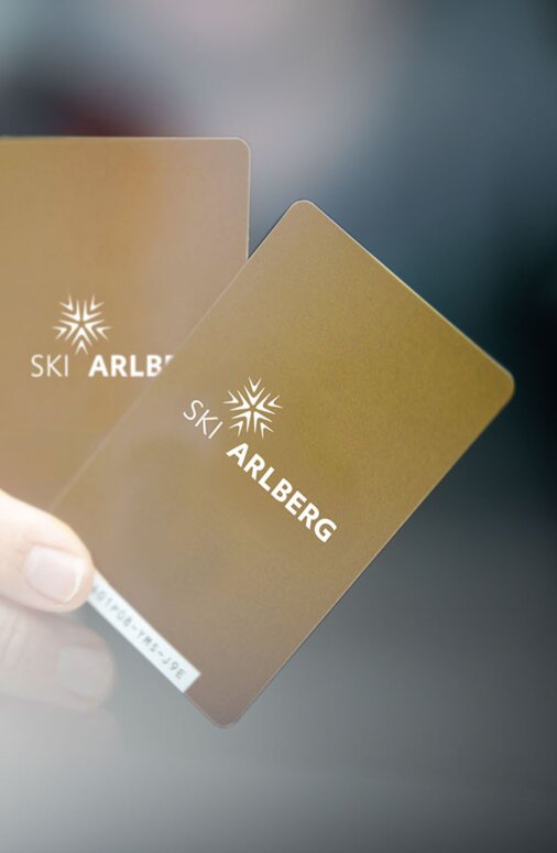 Close-up of two golden Ski Arlberg ski passes in a hand.