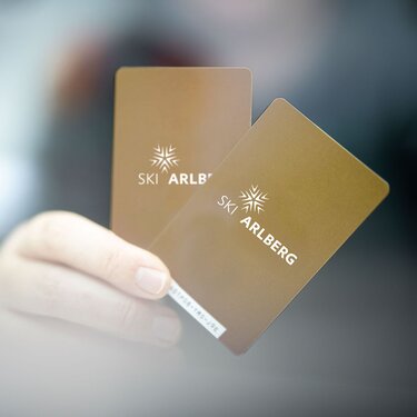 Close-up of two golden Ski Arlberg ski passes in a hand.
