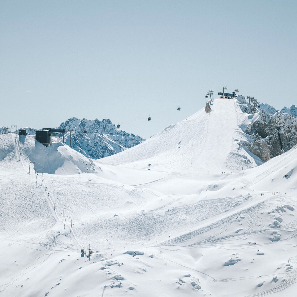 Snowy mountains with ski lift and slopes, blue sky.