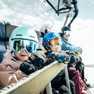 Children with ski gear on a chairlift in St. Anton am Arlberg ski resort.