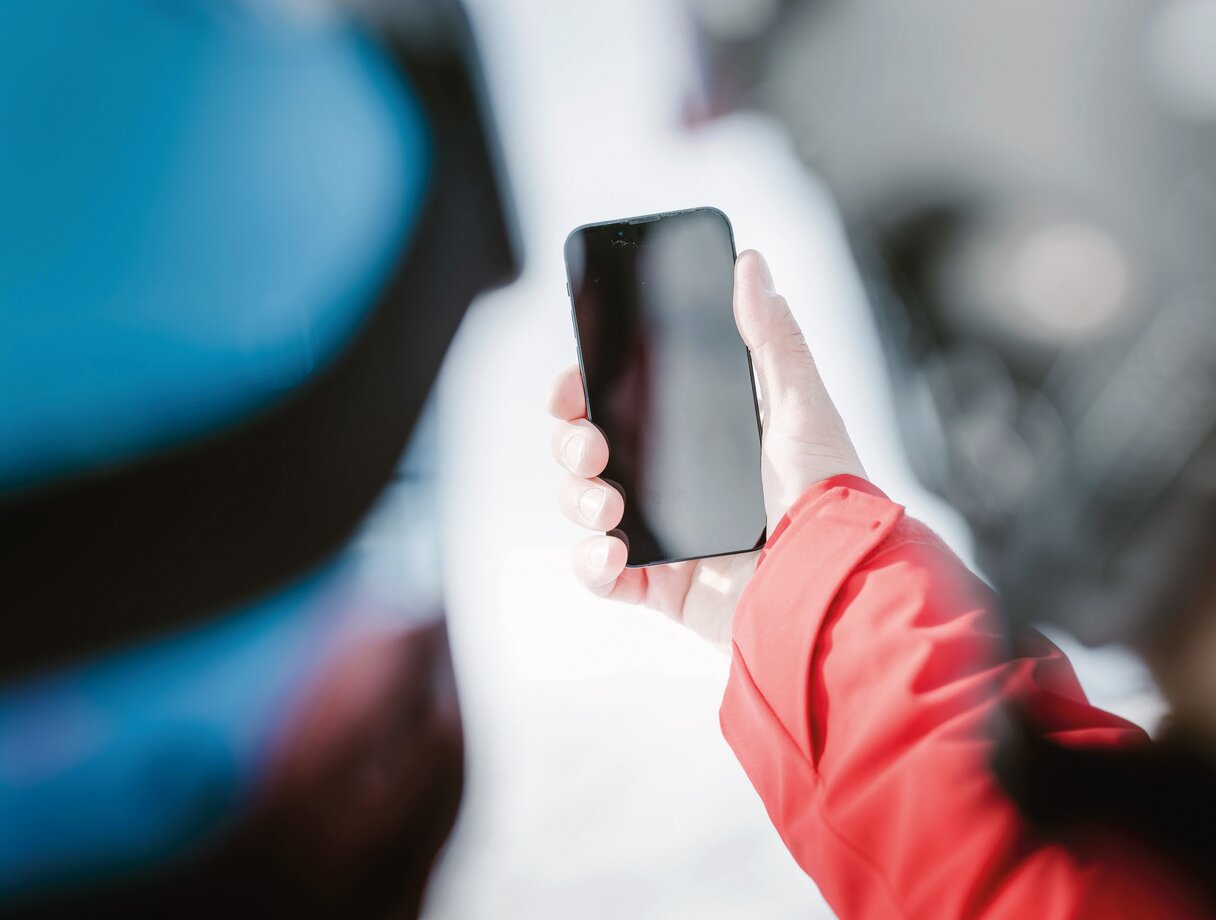 Person in red jacket holding a smartphone in St. Anton am Arlberg ski region.
