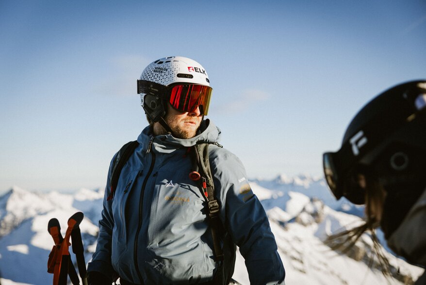 Mann mit Skiausrüstung und Helm in schneebedeckten Bergen.