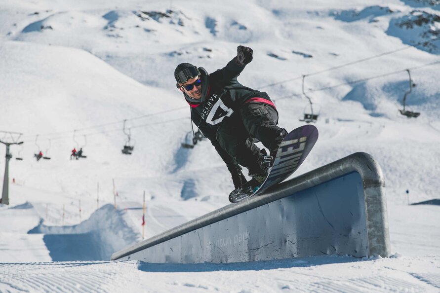 Snowboarder führt einen Carving-Trick auf einer Box aus.