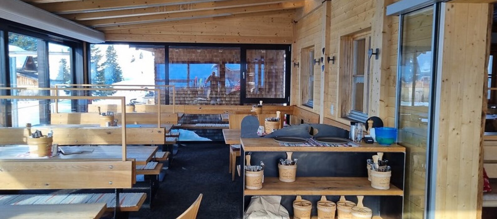 Conservatory at Berggasthof Aufelder Hütte with wooden decor and panoramic windows.