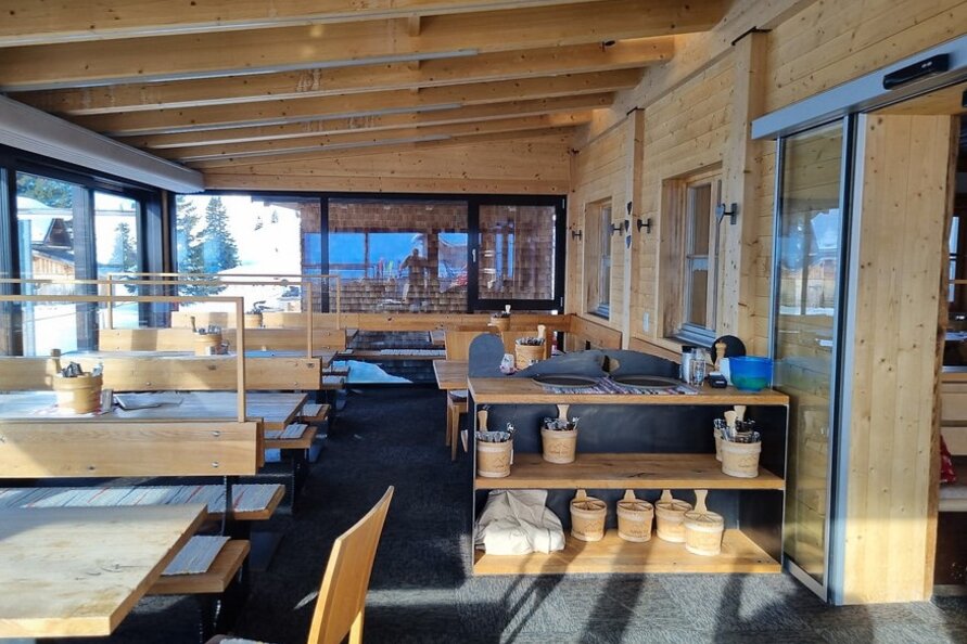 Wintergarten der Aufelder Hütte mit Holzeinrichtung und Panoramafenstern.