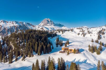 Schneebedeckte Berge mit dem Berghotel Körbersee im Vordergrund.