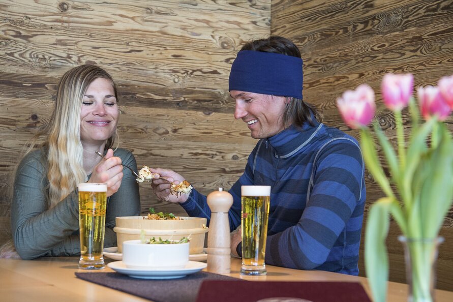 Zwei Personen genießen ein Essen mit Getränken in der S1 Skilounge.