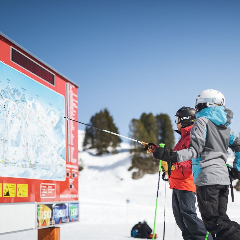 Zwei Skifahrer studieren eine Pistenkarte im Skigebiet Ski Arlberg.
