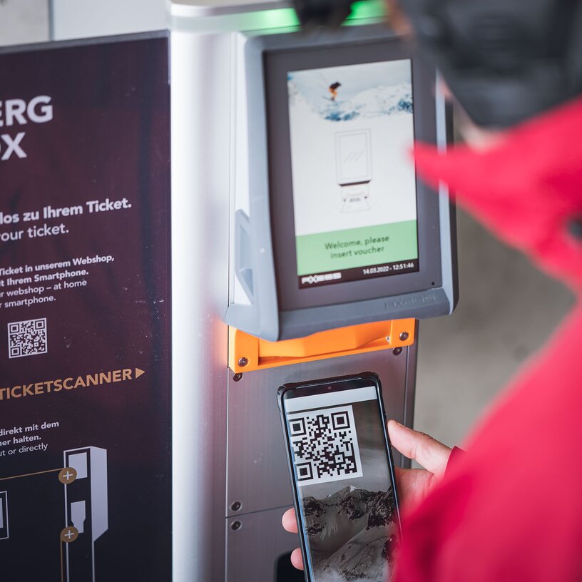 Person scanning QR code at a Ski Arlberg ticket machine.