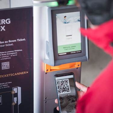 Person scannt QR-Code an einem Ski Arlberg Ticketautomaten.