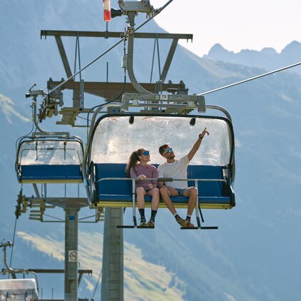 A couple riding a chairlift with a mountain view.