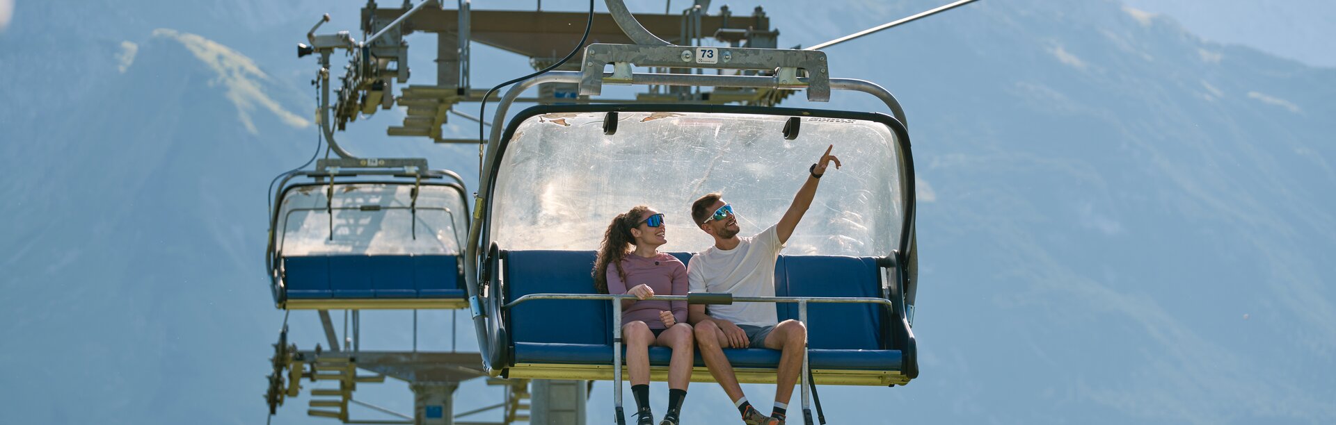 Ein Paar fährt in einem Sessellift mit Bergblick.
