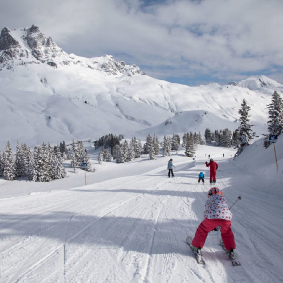 Skiers on a snowy slope with mountain scenery.