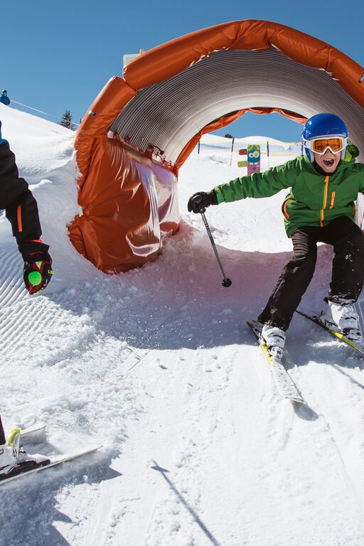 Zwei Kinder fahren beim Kidscross Salober durch einen Schneetunnel.