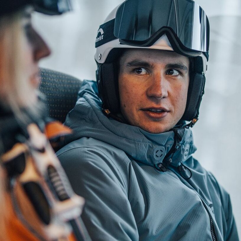 Zwei Skifahrer im Gespräch in einer Gondel.