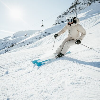 Person in ski gear skiing energetically downhill.