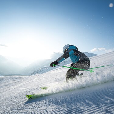 Skier in action on a snowy slope under sunny skies.
