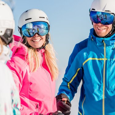 Three people in ski gear enjoying the sunshine.