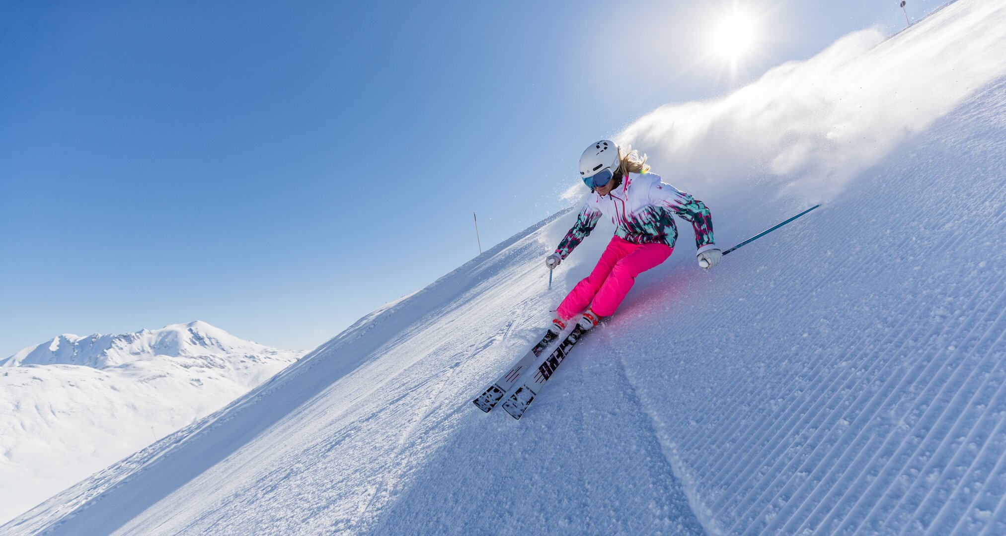 Skier in pink pants on a sunny slope.