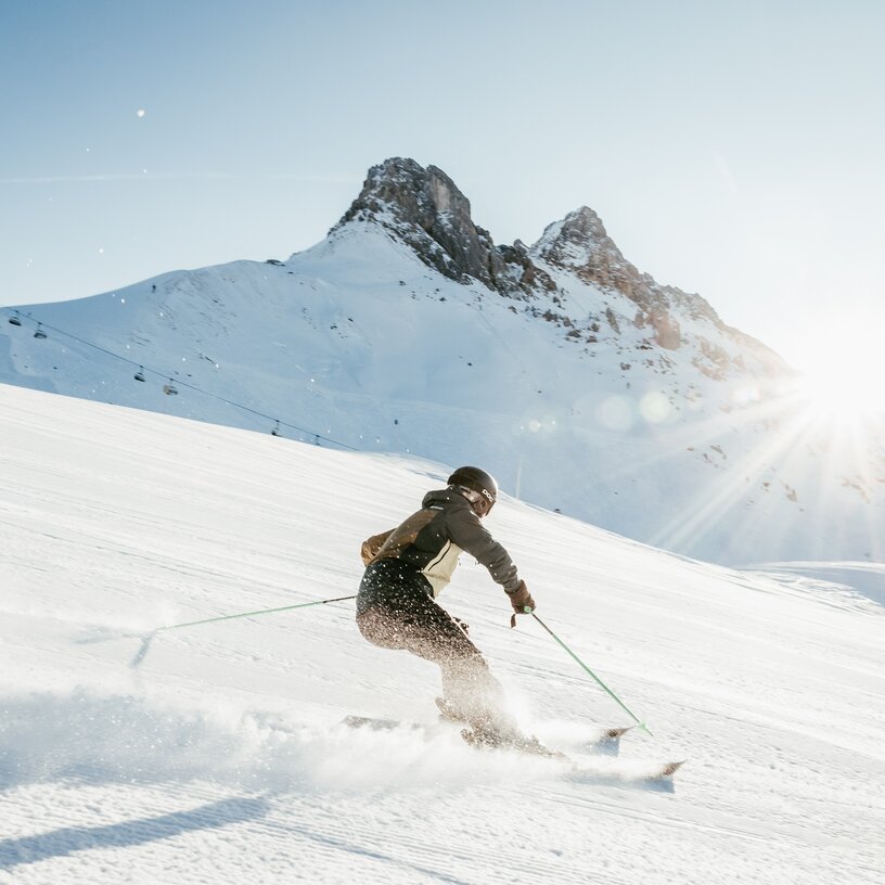Person skiing down a snow-covered mountain in the sunshine.