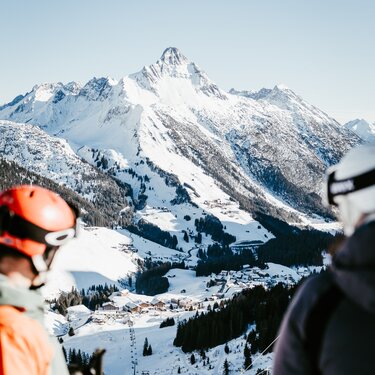 Zwei Skifahrer blicken auf die verschneiten Berge der Skiregion Warth-Schröcken.