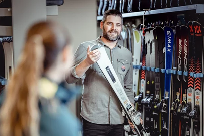 Ein Verkäufer zeigt einer Kundin Ski in einem Skiausrüstungsgeschäft.