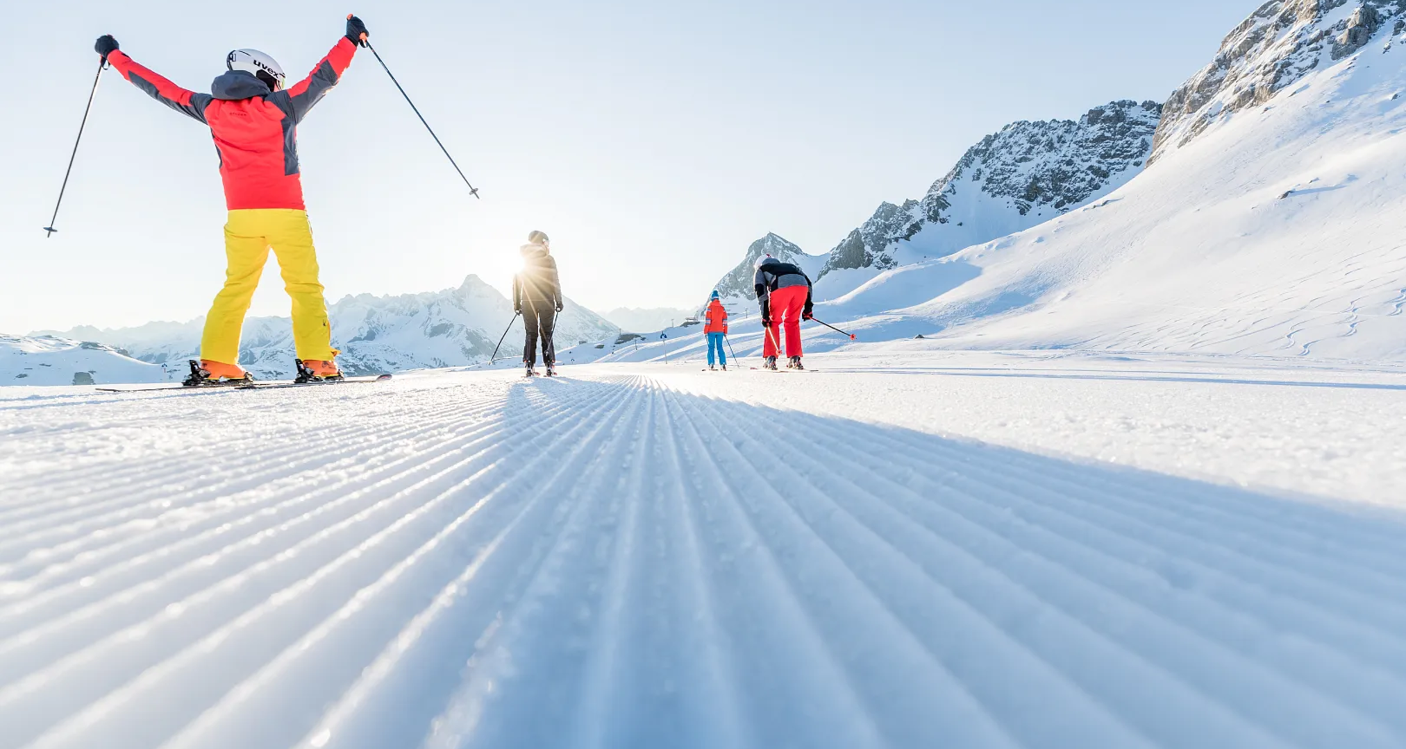 Skifahrer auf einer präparierten Piste bei Sonnenschein in den Bergen.