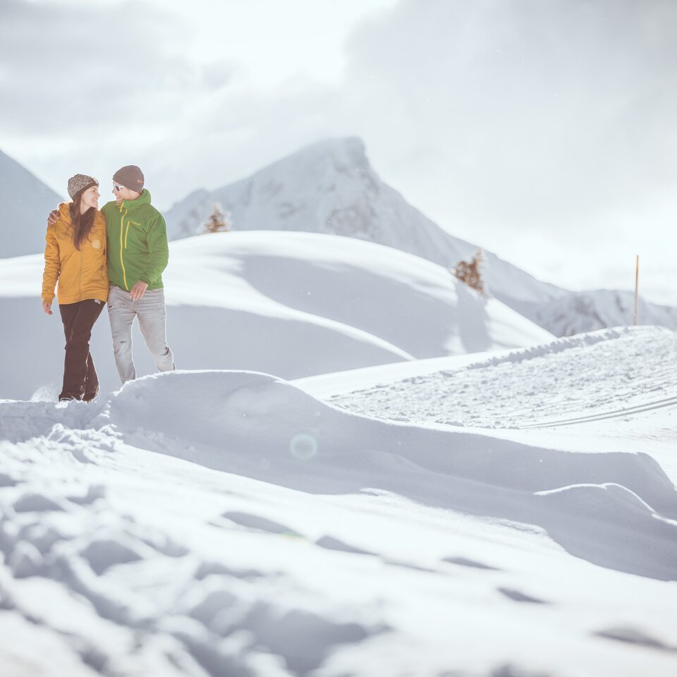 Ein Pärchen spaziert im Schnee vor einer malerischer Bergkulisse in Warth-Schröcken.